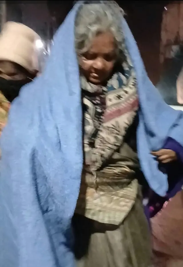 An elderly woman wrapped in a new blanket on a winter night